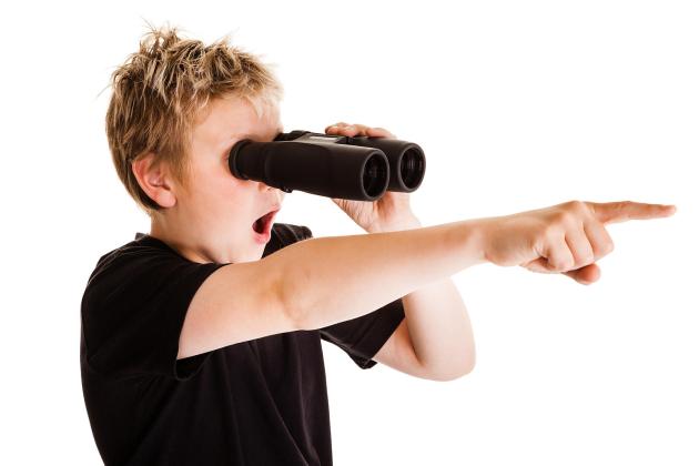 Teenage boy looking through binoculars and pointing with his finger